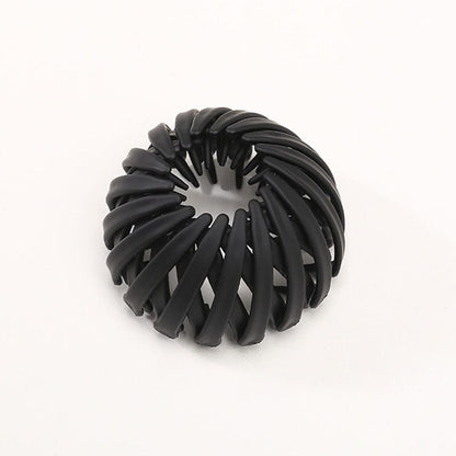 Matte Haarklammer in Schwarz mit spiralförmig angeordneten Rippen, einzeln vor hellem Hintergrund.