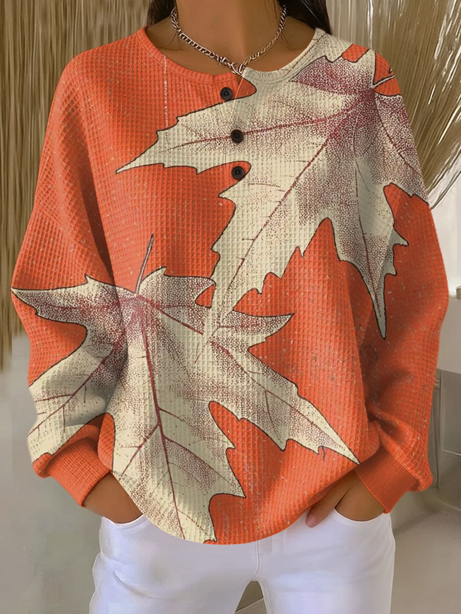 Orangefarbener Waffelstrick-Pullover mit Knopfleiste und großen cremefarbenen Ahornblättern als Motiv. 14