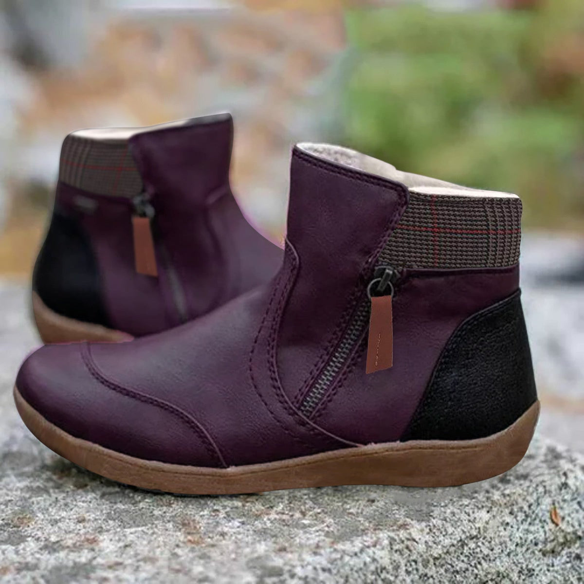 Violette Stiefeletten mit seitlichem Reißverschluss, brauner Lasche, kariertem Schaftrand und heller Gummisohle, Detail.