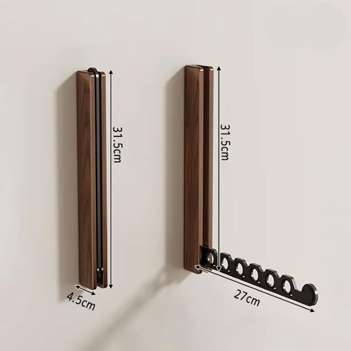 Maßdarstellung des Wandhakens aus dunklem Holz, eingeklappt und ausgeklappt, mit eingezeichneten Höhen-, Breiten- und Armlängenangaben. 10