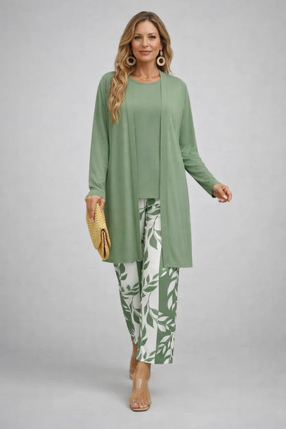Frau im salbeigrünen Set aus langem Cardigan und Shirt, dazu Hose mit grün-weißem Blättermuster und gelbe Clutch. 10