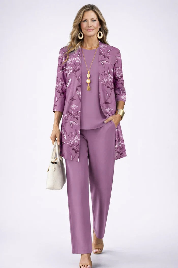 Frau im lila Set mit Blumenmuster auf dem Cardigan, dazu einfarbiges Shirt und weite Hose, Hand in der Hosentasche. 11