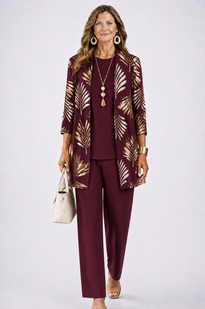 Frau im weinroten Set mit goldenem Palmblattmuster auf dem Cardigan, dazu weinrotes Shirt und weite Hose. 6