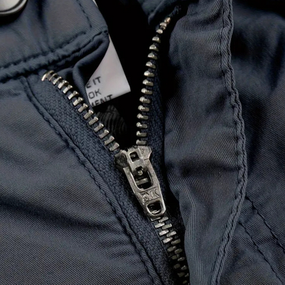 Dunkelblauer Reißverschluss an Jacke, Metallzähne, Nahaufnahme, robuste Outdoor-Bekleidung.