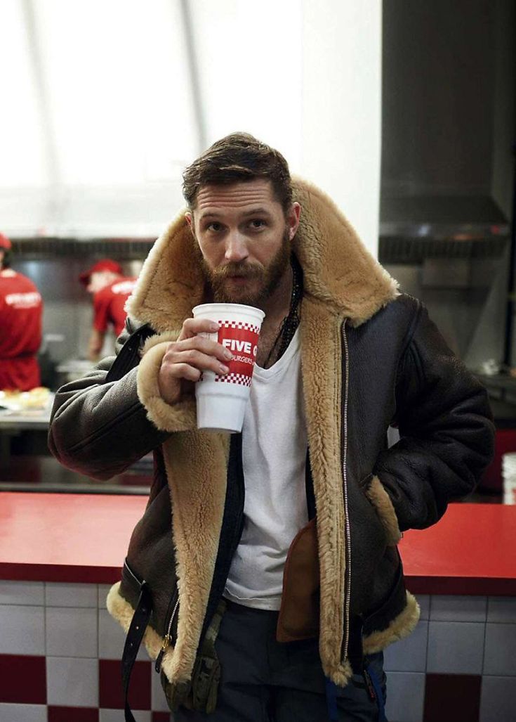 Bärtiger Mann trägt die Lederjacke mit dickem Fellkragen über weißem T-Shirt und trinkt aus einem Becher 4