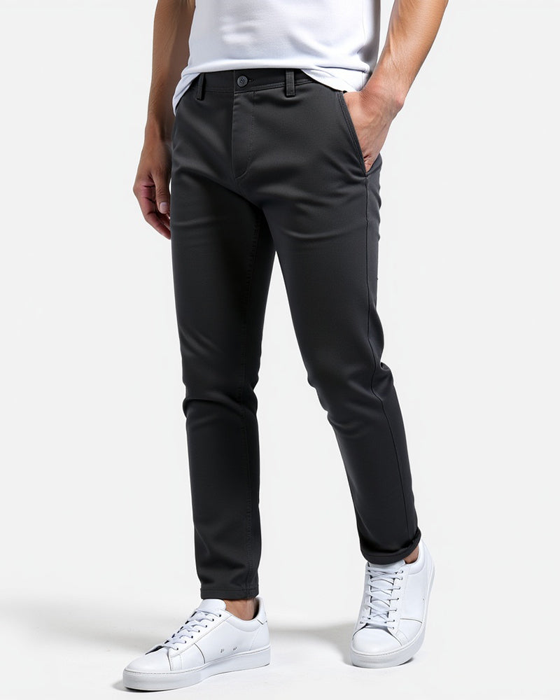 Dunkelgraue Chino seitlich von vorn mit weißem T-Shirt und weißen Sneakern, Beinabschluss leicht umgeschlagen.