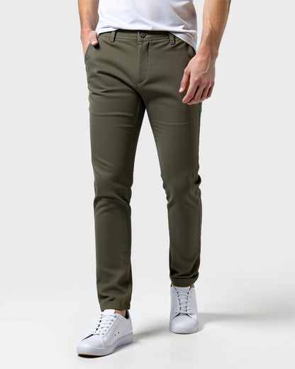 Olivgrüne Chino in der Frontansicht mit weißem Shirt und weißen Sneakern.