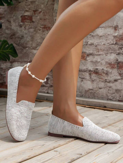 Helle, graumelierte Slip-on-Sneaker an den Füßen in Seitenansicht