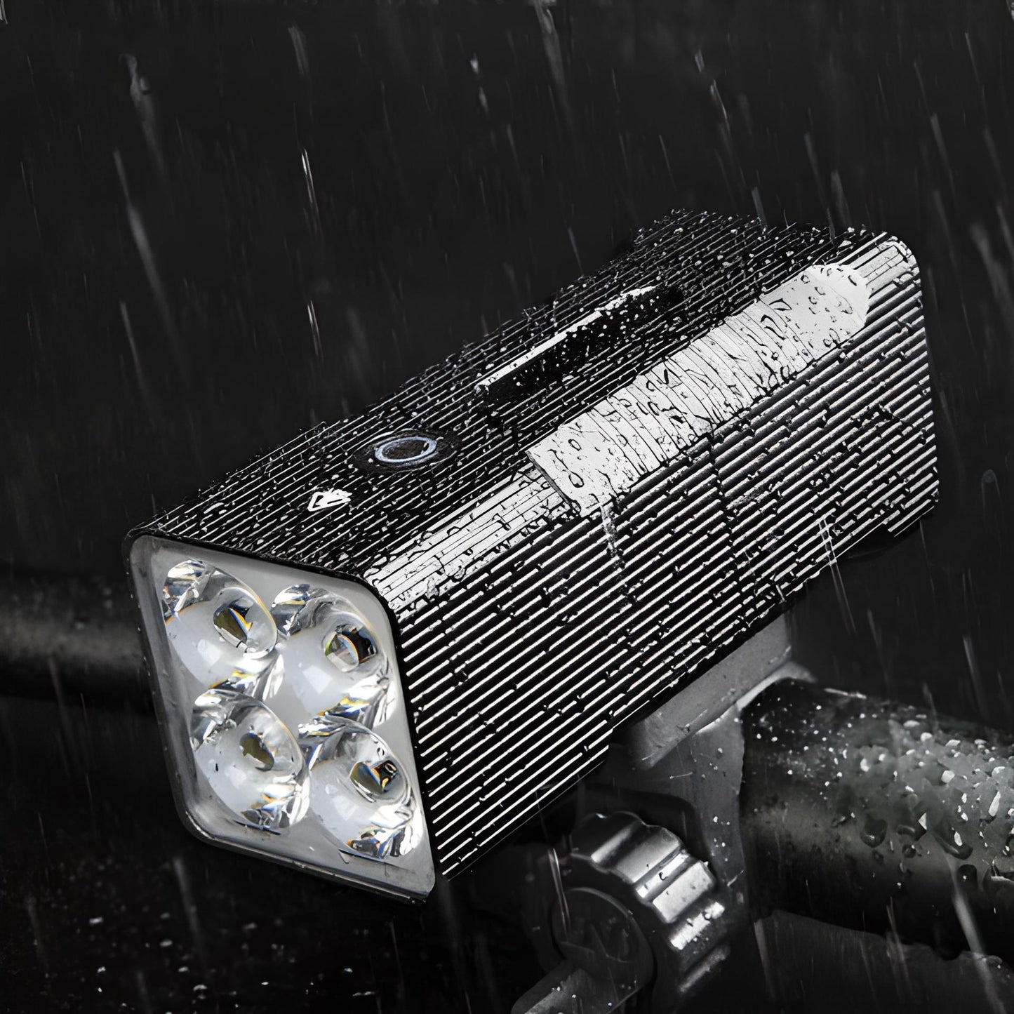Wasserdichte LED-Fahrradleuchte, schwarz, mit vier Linsen, montiert auf Lenker im Regen.