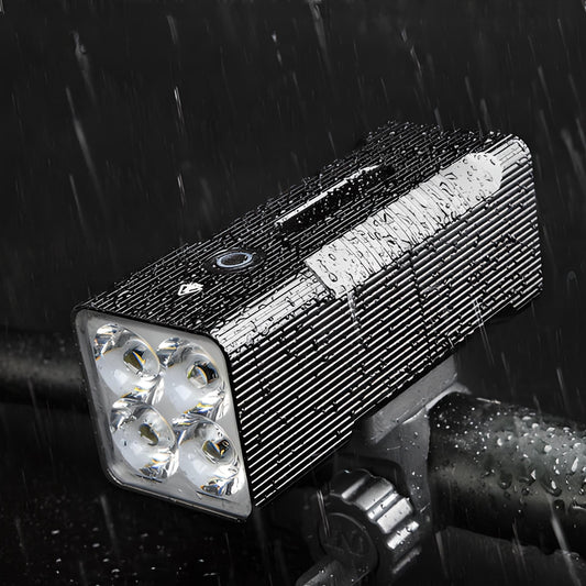 Wasserdichte LED-Fahrradleuchte, schwarz, mit vier Linsen, montiert auf Lenker im Regen.