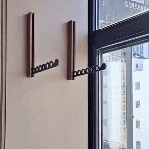 Zwei dunkle Holz-Wandhaken mit ausgeklapptem schwarzem Arm an einer hellen Wand neben einem Fenster. 2