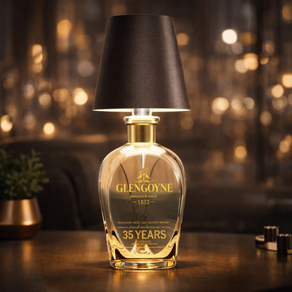 Dunkelbraune Flaschenlampe auf einer bauchigen Whiskyflasche mit goldenem Hals vor warmem Bokeh 13