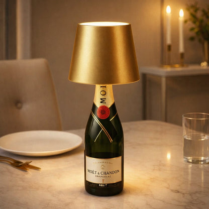 Goldene Flaschenlampe auf einer Champagnerflasche, gedeckter Tisch mit Teller, Glas und Kerzen im Hintergrund 17