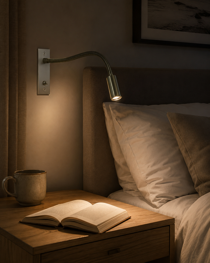 Silberfarbene Schwanenhals-Wandlampe über einem Bett mit aufgeschlagenem Buch