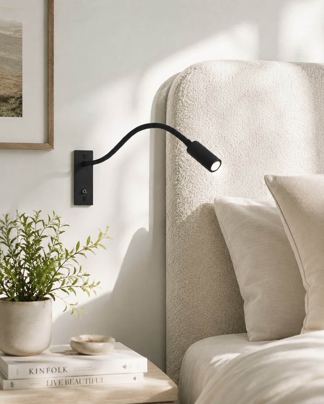 Schwarze Schwanenhals-Wandlampe an heller Wand neben einem Bett mit cremefarbenem Bouclé-Kopfteil