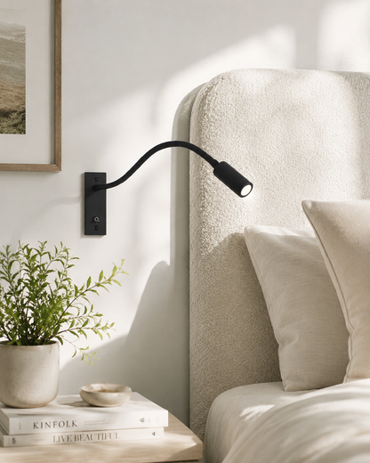 Schwarze Schwanenhals-Wandlampe an heller Wand neben einem Bett mit cremefarbenem Bouclé-Kopfteil