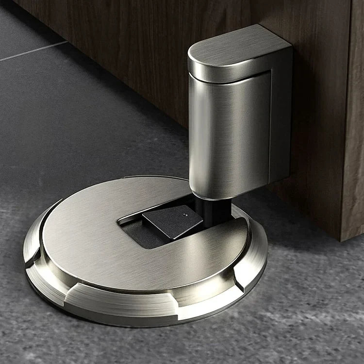Silberfarbener Türstopper in gebürstetem Metall auf grauem Boden, der Arm liegt an einer Holztür an 9