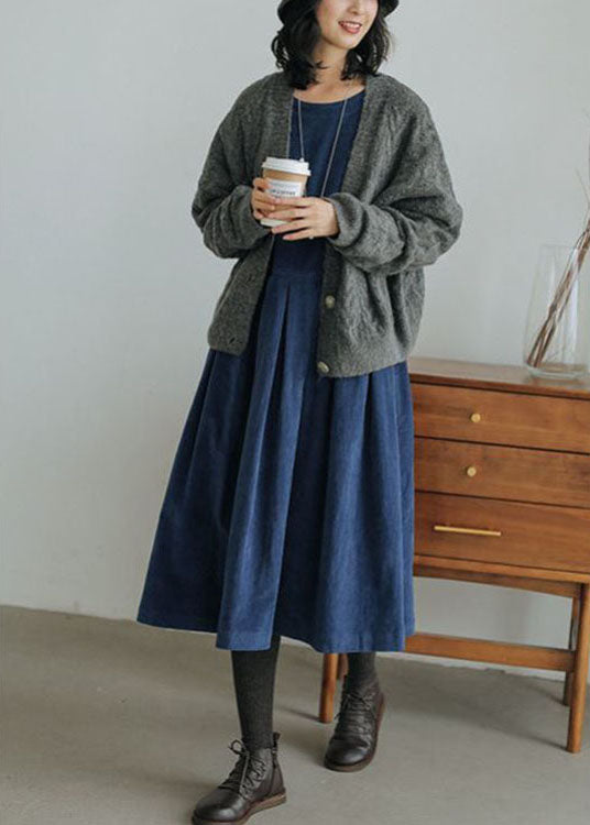 Frau in blauem Denim-Kleid mit grauer Strickjacke, hält Kaffeebecher, Herbstmode.