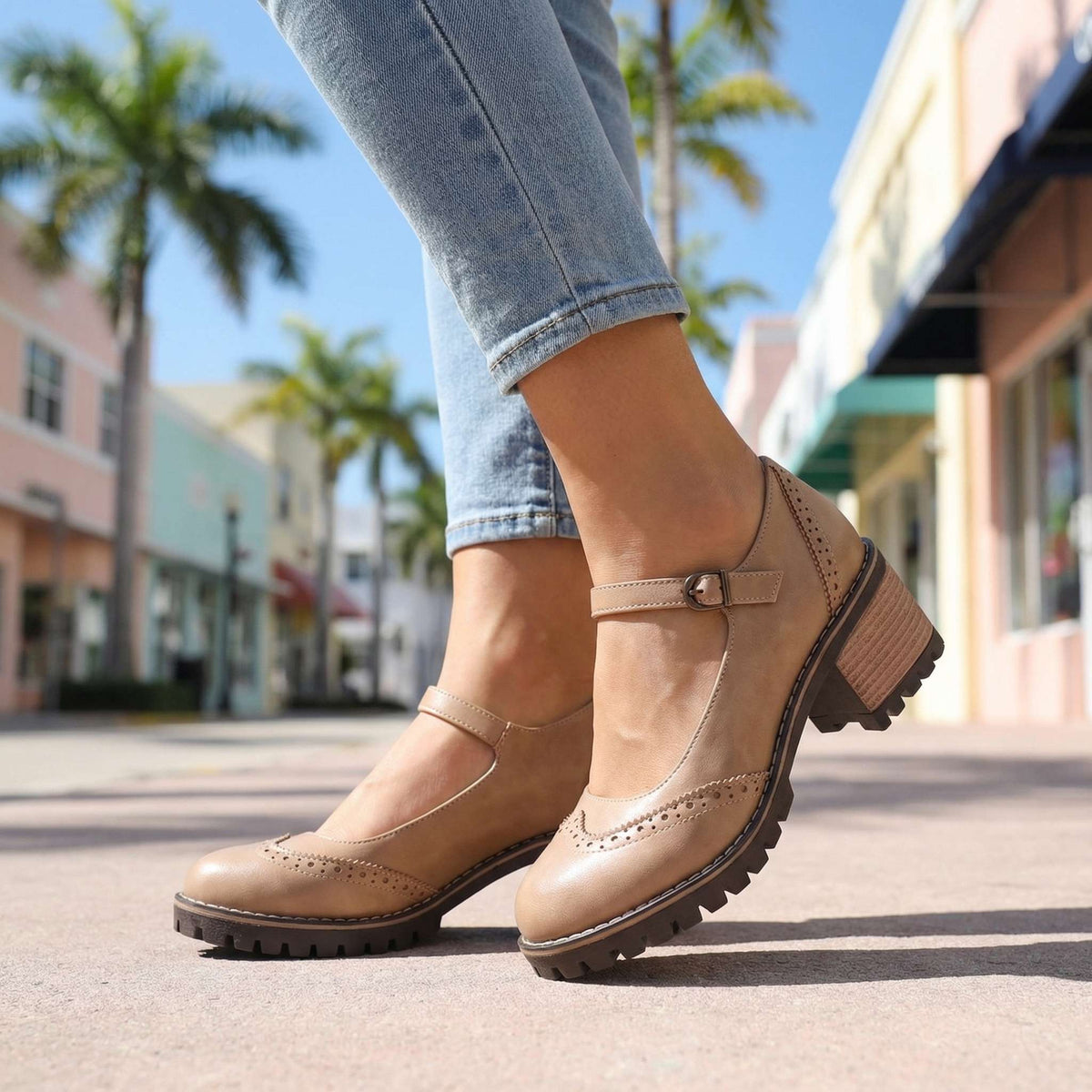 Beige Mary Janes mit verstellbarem Riemen, Lochverzierung und profilierter Sohle, getragen zu Jeans in einer sonnigen Straße. 9