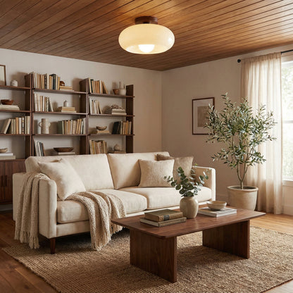 Große Deckenleuchte hängt an einer Holzdecke über cremefarbenem Sofa, Couchtisch und Olivenbaum 2