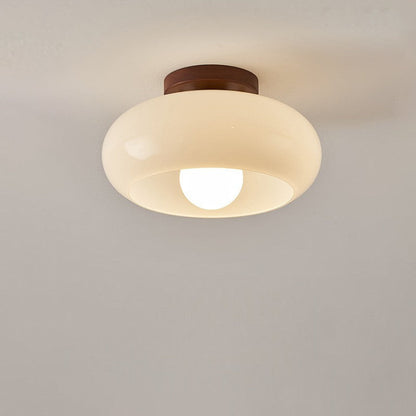 Frontale Ansicht der eingeschalteten Leuchte mit rundem cremefarbenem Glasschirm und sichtbarer Glühbirne an heller Decke 6