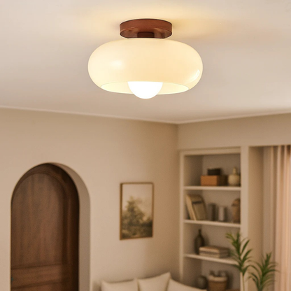 Leuchtende cremefarbene Glasleuchte mit Holzbaldachin an der Decke eines Wohnzimmers mit Rundbogentür und Regal 1