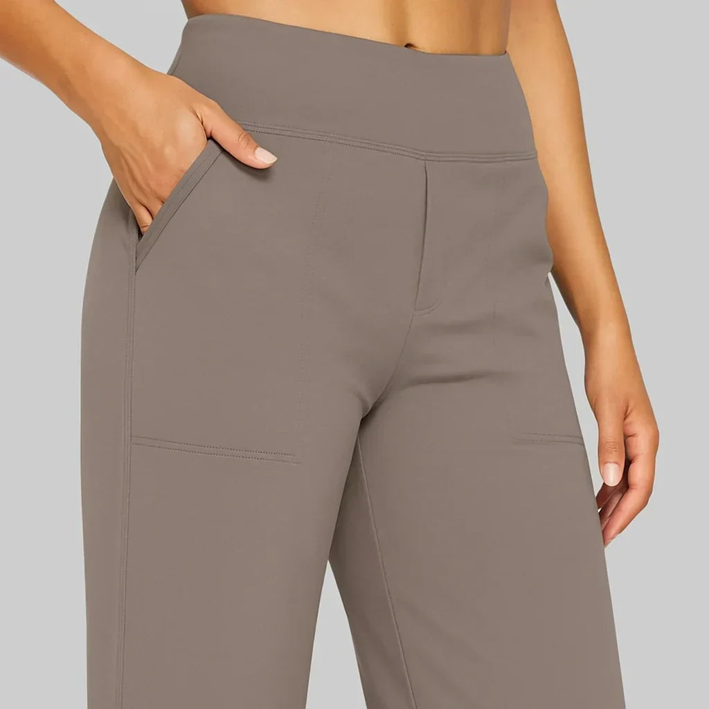 Nahaufnahme von Bund, Seitentasche und aufgesetzter Tasche der taupefarbenen Hose, eine Hand steckt in der Tasche. 3