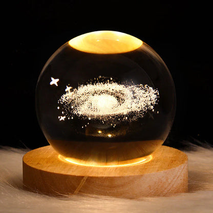Leuchtende Kristallkugel mit Galaxie-Design auf Holzsockel, dekorative LED-Lampe.
