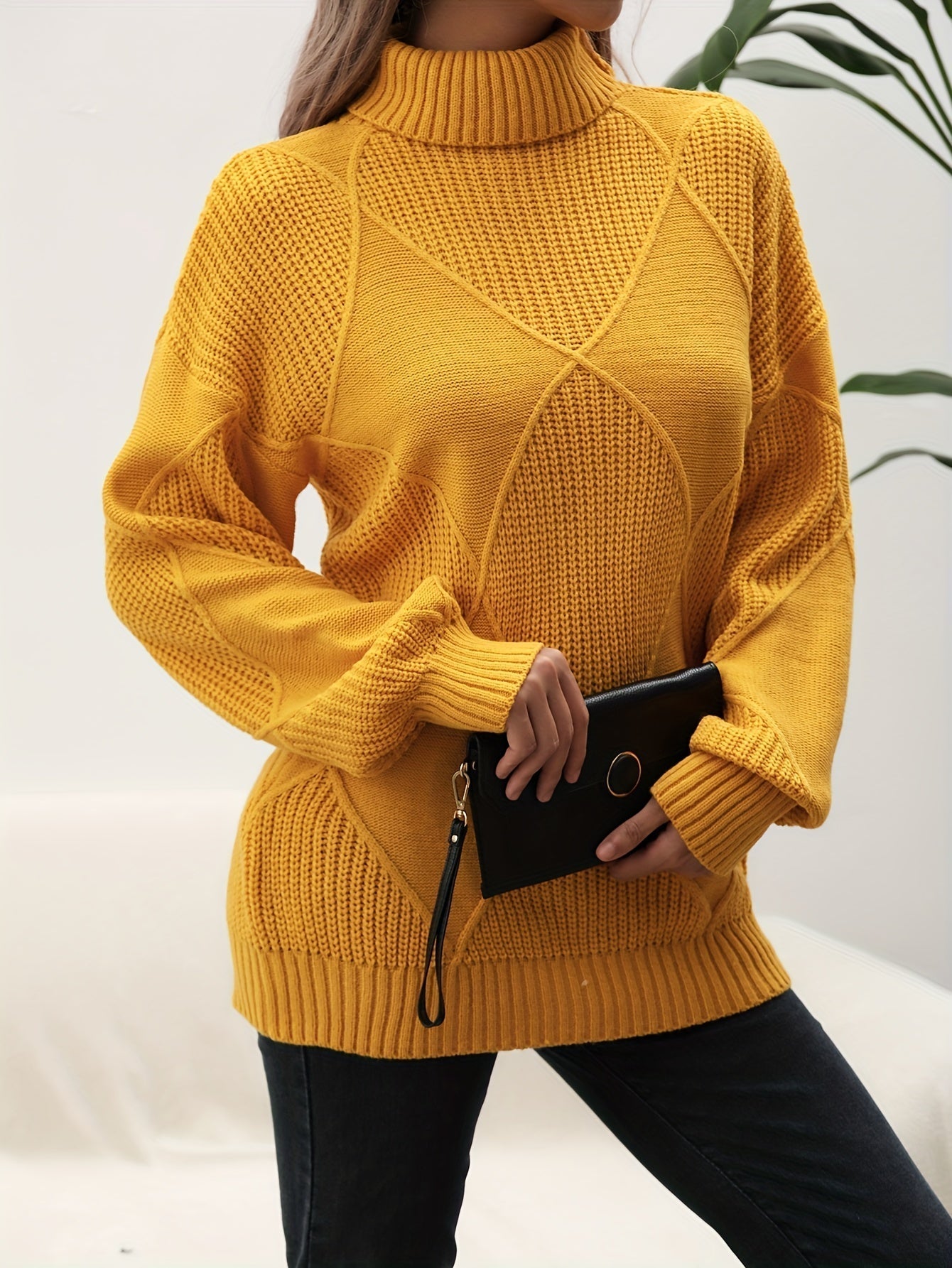 Frau in gelbem Strickpullover mit Rollkragen, hält schwarze Clutch, modisch, elegant.