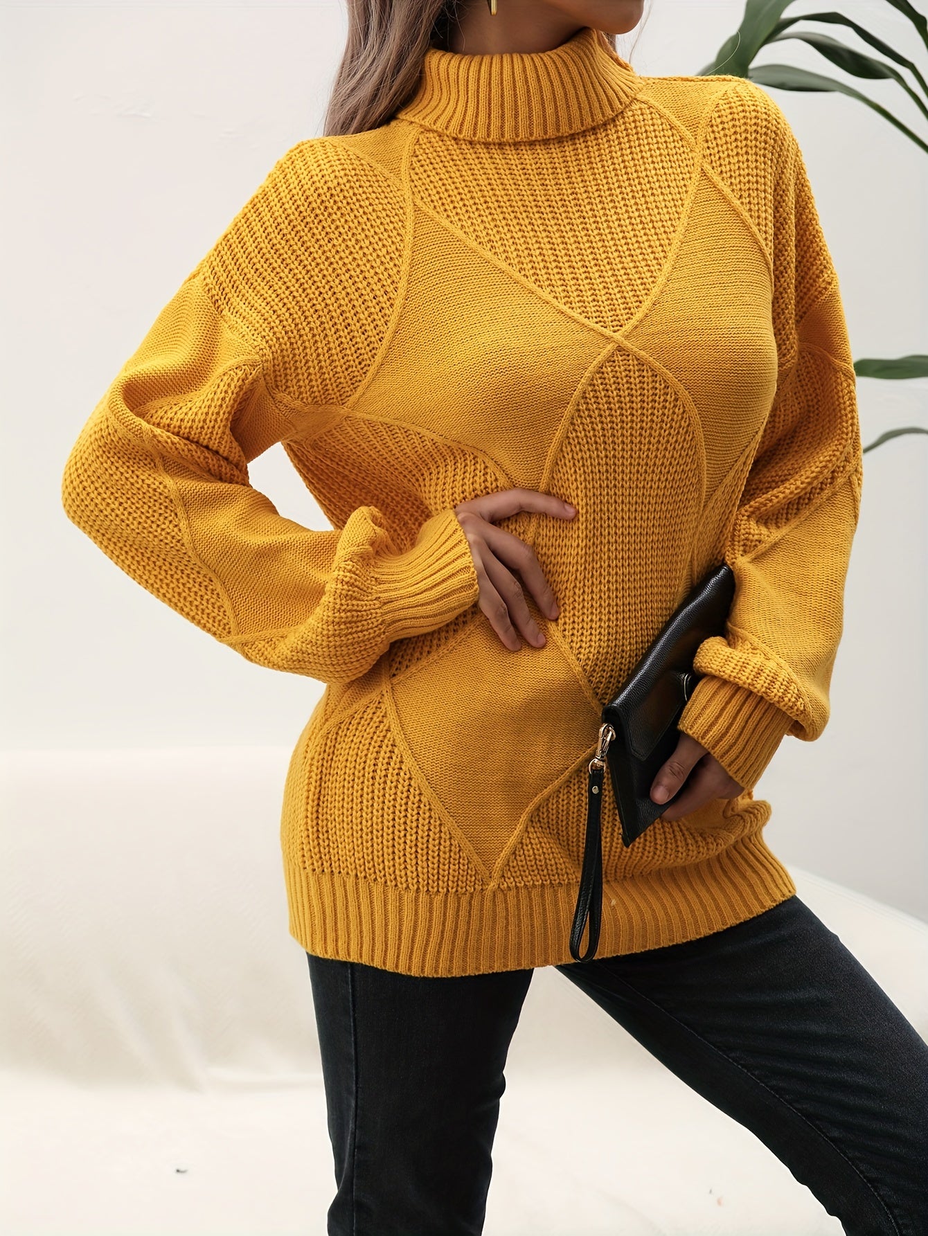 Frau in gelbem Strickpullover, Rollkragen, hält schwarze Clutch, modisch, Herbstmode.