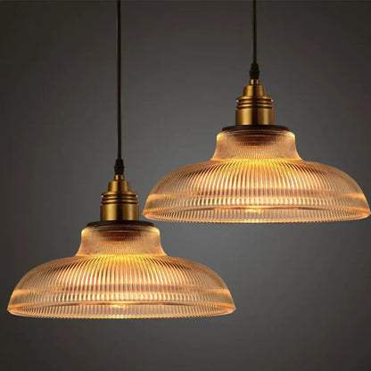Zwei hängende Vintage-Pendelleuchten aus Glas mit warmem Licht, ideal für Wohnzimmerbeleuchtung.