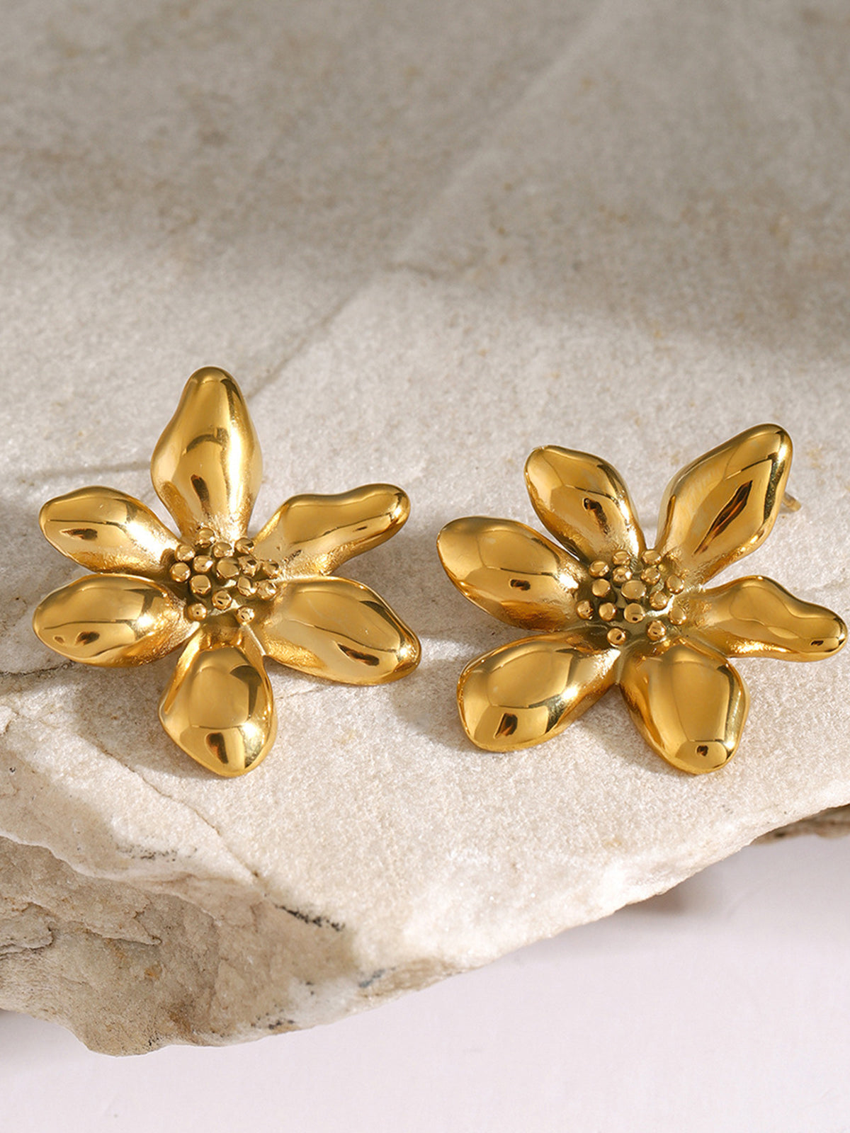 Goldene Blumen-Ohrringe auf Stein, eleganter Schmuck, modische Accessoires, glänzend, Damen.