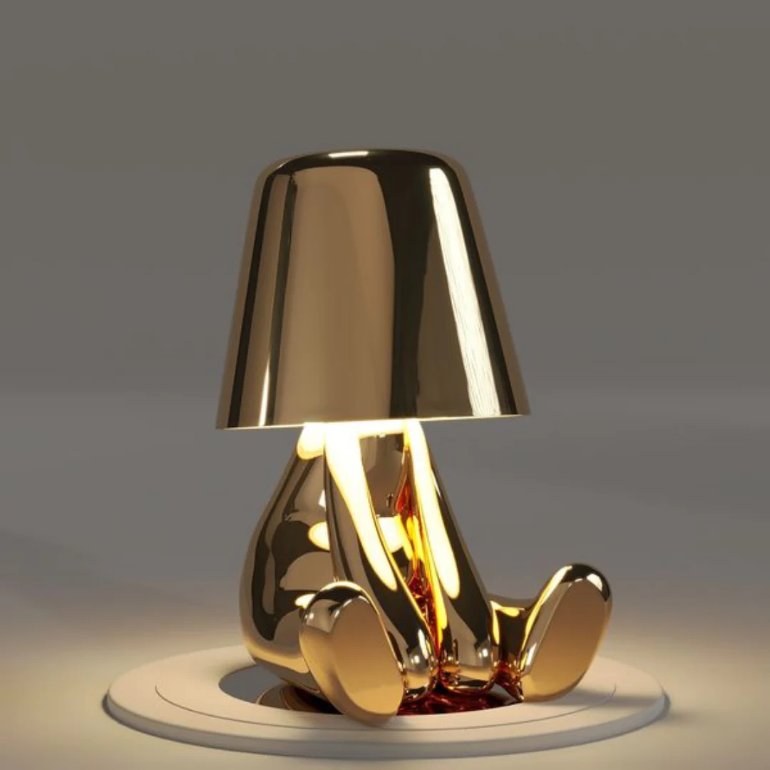 Goldene Tischlampe in Form einer sitzenden Figur, modernes Design, glänzend, dekorativ.
