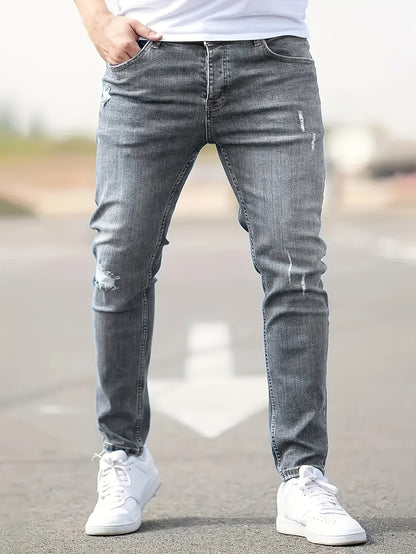 Graue Jeans für Herren, Slim Fit, mit leichten Rissen, lässiger Stil, Straßenhintergrund.