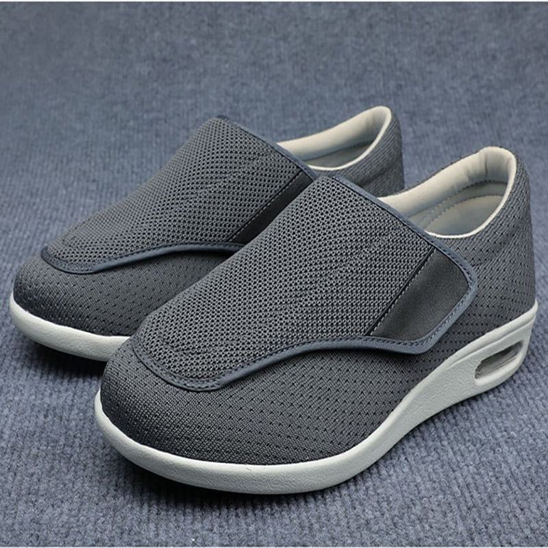 Graue orthopädische Schuhe für Herren, atmungsaktiv, bequem, rutschfest, auf Teppich.