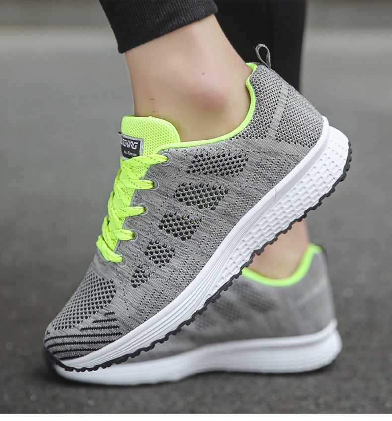Graue Sportschuhe mit neongelben Akzenten, atmungsaktivem Mesh-Obermaterial und weißer Sohle.