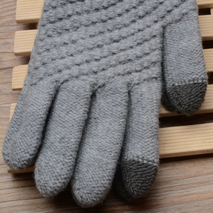 Grauer gestrickter Handschuh aus Wolle auf Holzuntergrund, winterfest, warm, modisch.