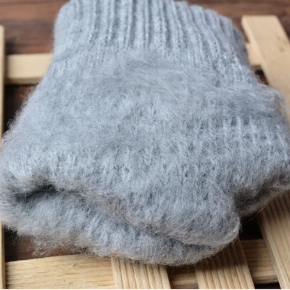 Graue Wollsocken aus Alpaka, handgestrickt, warm, weich, auf Holzuntergrund.