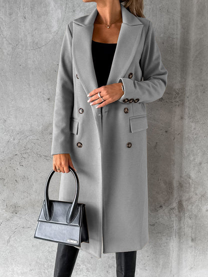 Frau in grauem Wollmantel mit Knöpfen, hält schwarze Handtasche, elegante Herbstmode.