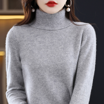 Grauer, leicht melierter Rollkragenpullover am Model mit feiner Strickstruktur und geripptem Kragen.