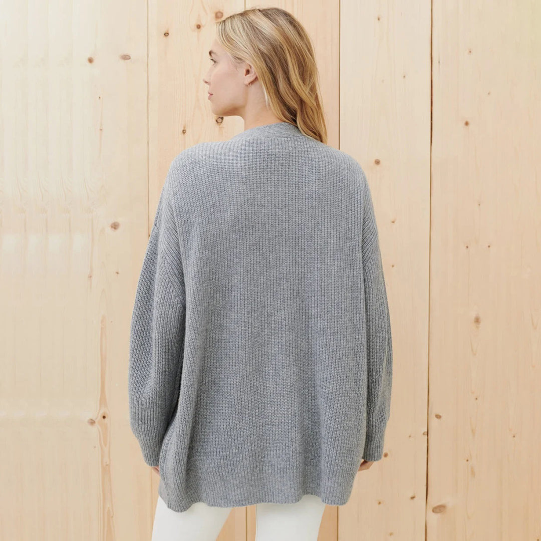 Frau in grauem Strickpullover, Rückansicht, vor Holzwand, lässige Mode, Herbstbekleidung.