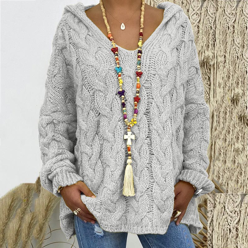 Frau in grauem Strickpullover mit bunter Halskette und blauer Jeans, lässige Herbstmode.