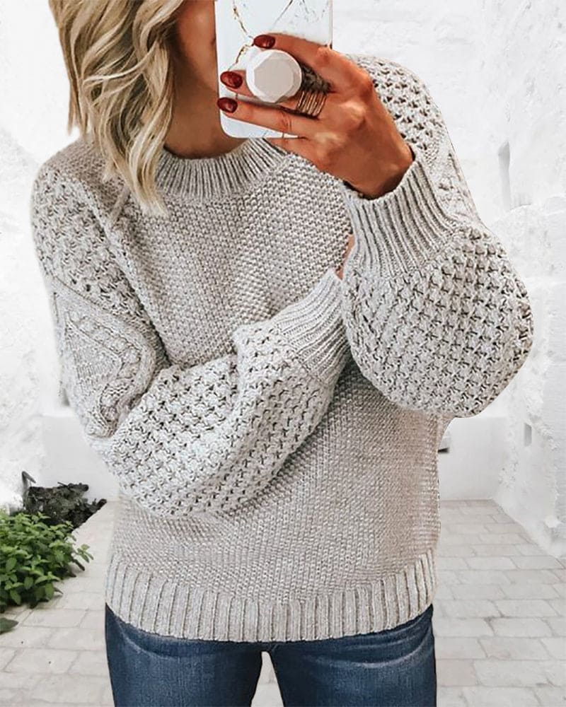 Frau in grauem Strickpullover mit Zopfmuster, lässig, modisch, Herbstmode, gemütlich.