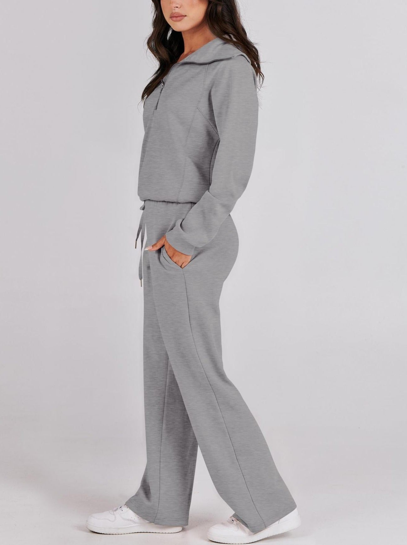 Frau in grauem Jogginganzug, Kapuzenpullover, weite Hose, Freizeitmode, bequem, sportlich.