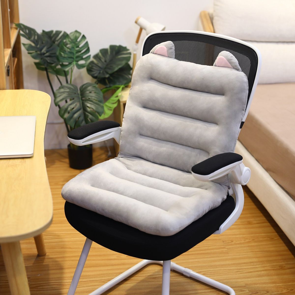 Ergonomischer Bürostuhl mit grauem Katzenohr-Kissen, Mesh-Rückenlehne, Holzfußboden.