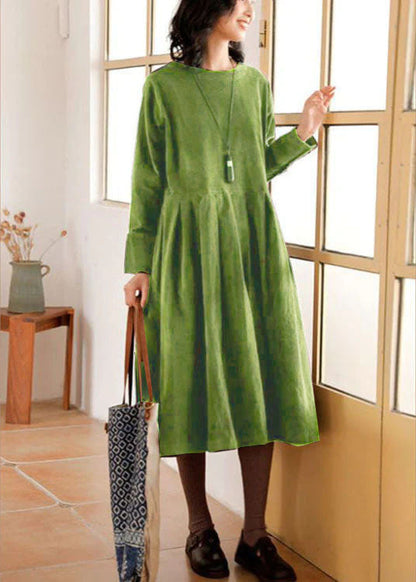 Frau in grünem Leinenkleid, steht am Fenster, hält eine Tasche, modisch, lässig, Herbstmode.