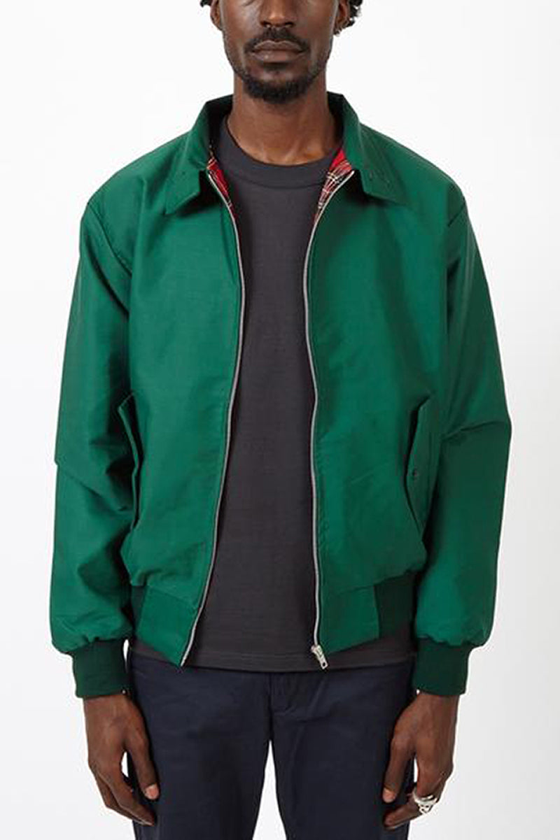 Mann trägt grüne Harrington-Jacke, schwarzes T-Shirt, dunkle Hose.