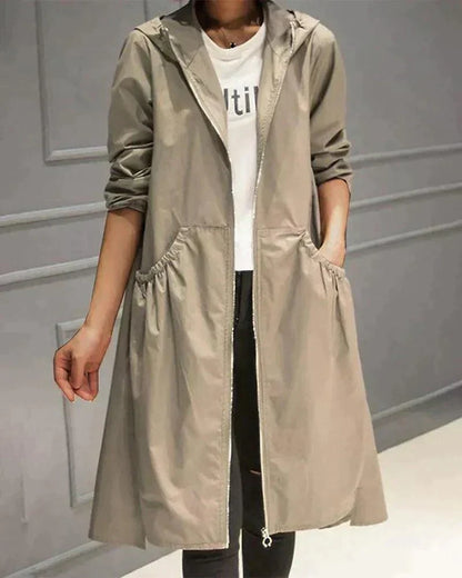 Modell trägt den offenen Regenmantel in Beige mit Kapuze und gerafften Eingrifftaschen, Vorderansicht 1