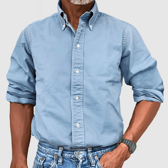 Mann in hellblauem Button-Down-Hemd aus Baumwolle, lässig gekrempelt, mit Jeans.