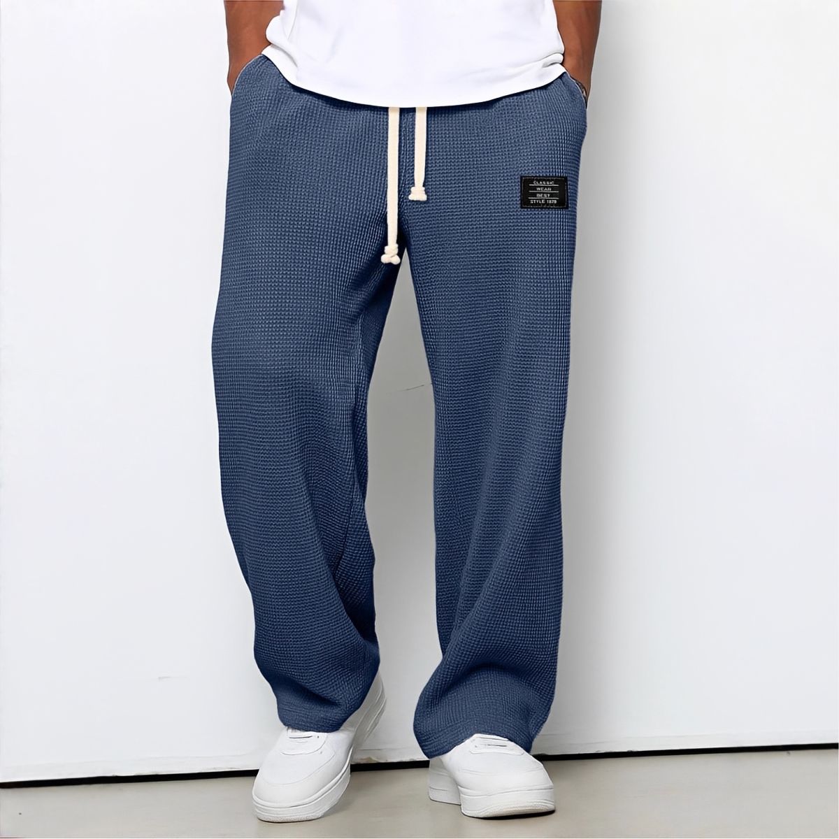 Frontansicht der Waffelstrick-Hose in Marineblau mit weißem Kordelzug, getragen mit weißem Shirt und Sneakern 5